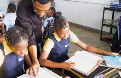 Teacher helping two female students at a desk.